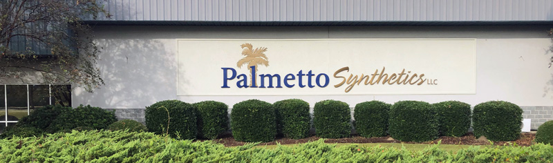 Palmetto Sythetics logo on building with bushes infront